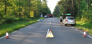 Na drodze trójkąt ostrzegawczy wypadek, przewrócony motocykl, straż i 2 samochody.