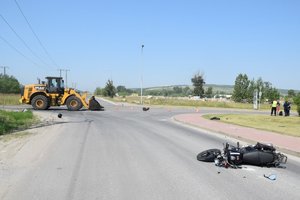 Na skrzyżowaniu koparka z ładowarką, w niedalekiej odległości przewrócony motocykl.