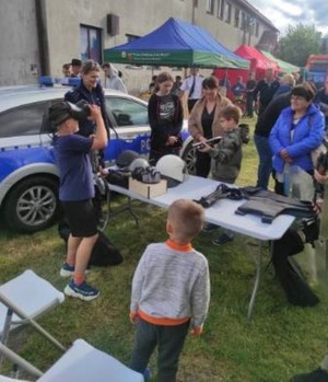 Radiowóz i wokół policjantka i grupa dzieci.
