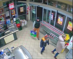 Mężczyzna z torbą wchodzi do sklepu, obok kobieta z dzieckiem.