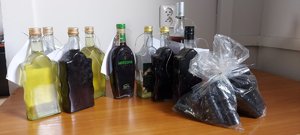 Szklane butelki z zawartością płynną na biurku, obok foliowa torebka.