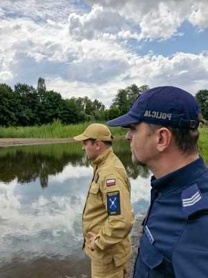 Policjant i strażak kontrolują zbiornik wodny.