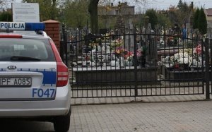 Radiowóz obok bramy wjazdowej na cmentarz.