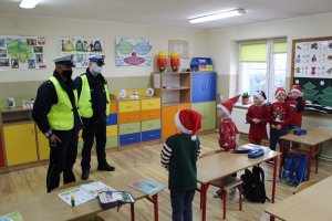 Wizytacja policjantów w szkole. Niektóre dzieciaki z czapkami mikołaja.