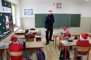 Wizytacja policjantów w szkole. Niektóre dzieciaki z czapkami mikołaja.