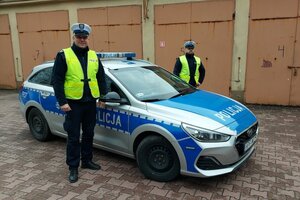 Dwóch policjantów przy radiowozie.