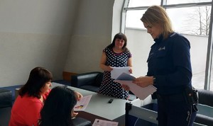 Umundurowana policjantka w pomieszczeniu MOSiR  wręcza ulotkę informacyjną kobiecie.