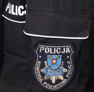 Widoczna część rękawa munduru policyjnego z napisem Policja.