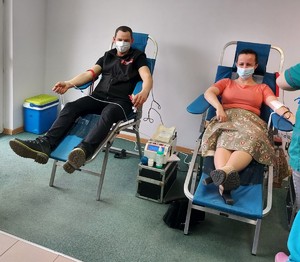 Mężczyzna i kobieta oddają krew. Siedzą na fotelach.