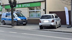 Radiowóz i samochód osobowy stojące na chodniku.