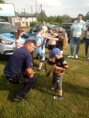 Przed radiowozem policjant i grupa dzieci.