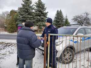 Policjant z pracownikami socjalnymi rozdają ciepłe posiłki potrzebującym.