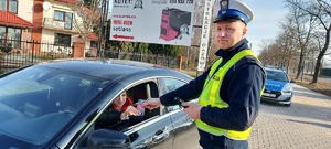 Policjant wręcza zapachowe serduszko walentynkowe kierującej.