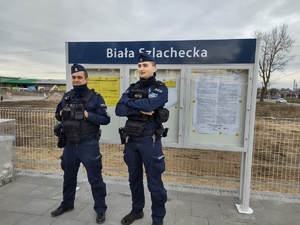 Dwóch umundurowanych policjantów stoi na peronie.