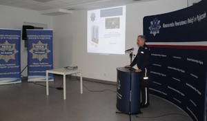 Na zdjęciu widać jak umundurowany policjant przemawia.