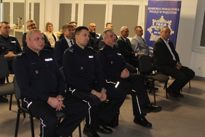 Na zdjęciu widać siedzących policjantów i osoby cywilne.