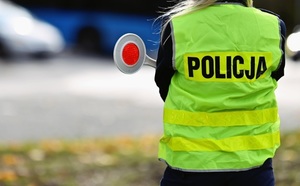 Zdjęcie pleców policjanta w kamizelce odblaskowej.