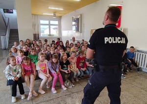 Grupa dzieci, przed nimi policjant.