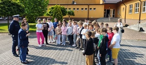 Grupa dzieciaków, przed nimi policjant.