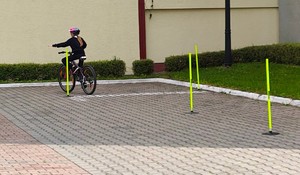 Dziewczynka jedzie rowerem po specjalnym torze.