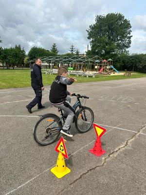 Chłopiec jedzie specjalnym torem, obok policjant.