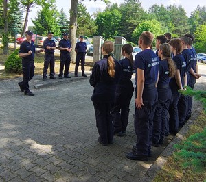 Uczniowie klasy mundurowej stoją w grupie, przed nimi stoi dwóch policjantów i policjantka.