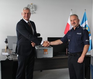 Policjant i mężczyzna ściskują  prawe dłonie.