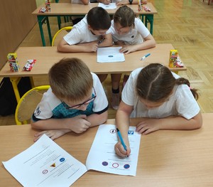 Dzieci siedzą w ławkach.