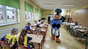 Dzieci siedzą w ławkach.