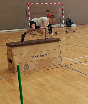 Chłopiec przeskakuje przez skrzynię.