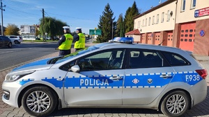 Policjanci stoją przy radiowozie.