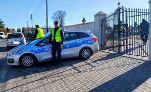 Policjanci stoją przy radiowozie.