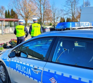Policjanci stoją przy radiowozie.