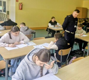 Policjant nadzoruje zawodników podczas testu teoretycznego.
