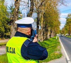 Umundurowany policjant dokonuje pomiaru prędkości.